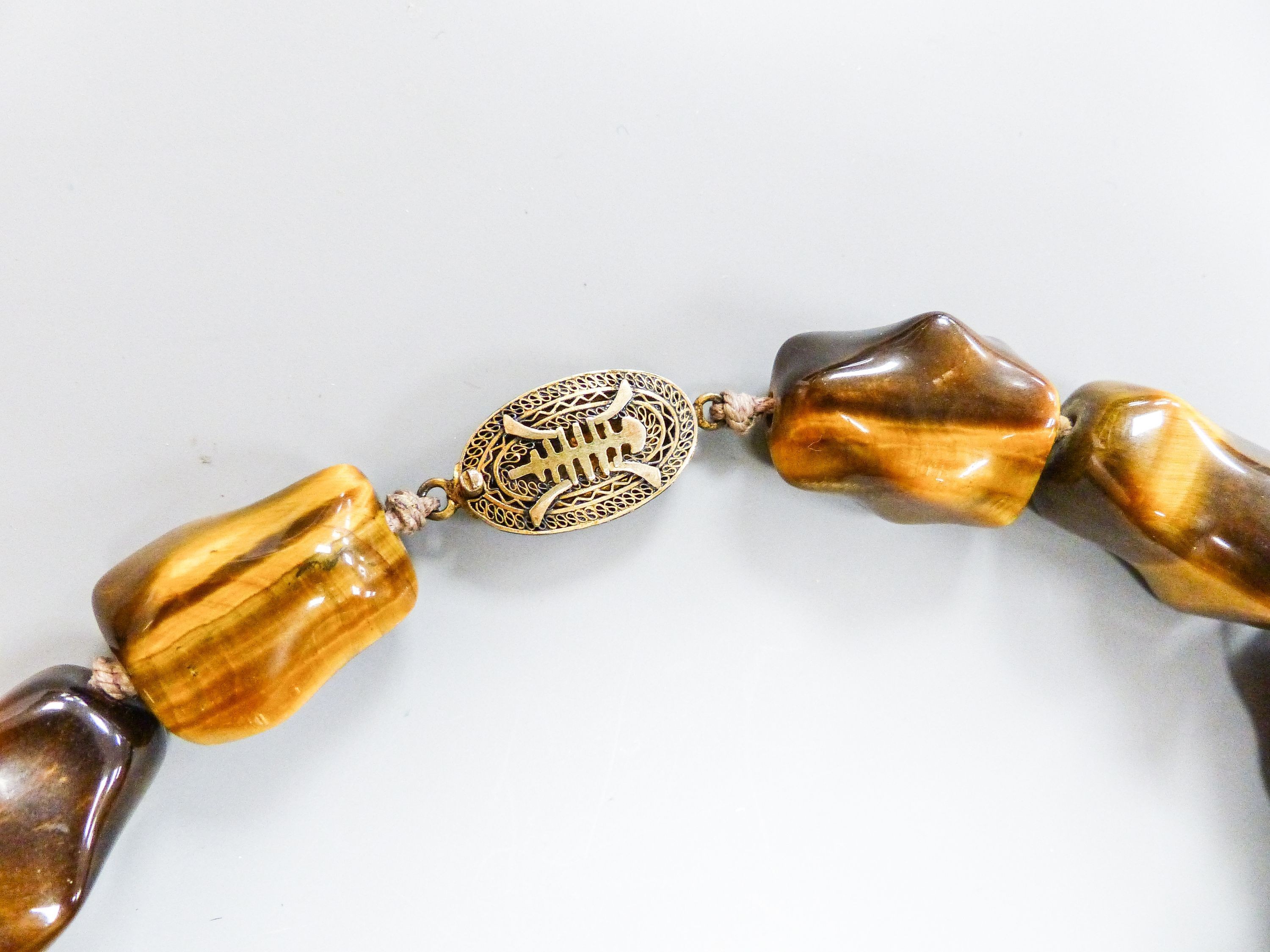 A Middle Eastern gilt white metal and tiger's eye pebble necklace, 48cm and a similar brooch and dress ring.